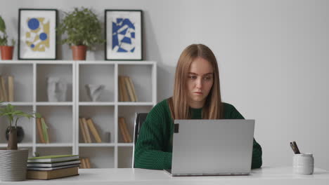 Una-Joven-Seria-Está-Haciendo-Tareas-Domésticas-En-Un-Servicio-En-Línea-Para-Estudiantes-De-Aprendizaje-Electrónico-Y-Autoeducación-Desde-Casa-Trabajando-Con-Una-Computadora-Portátil